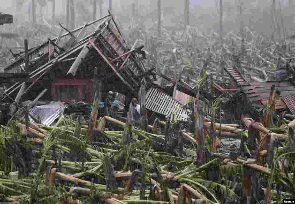 Typhoon victims stand outside their destroyed house after Typhoon Bopha in New Bataan town in Compostela Valley, Philippines, December 7, 2012. 