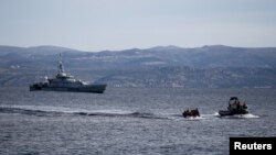 A rescue boat escorts a dinghy with migrants from Afghanistan as a Frontex vessel patrols in the background, on the island of Lesbos, Greece, February 28, 2020.