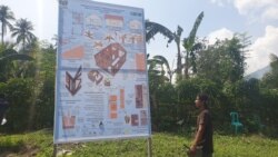 Seorang tukang membaca penjelasan mengenai membangun rumah tahan gempa dengan lapisan ferosemen yang terpampang pada sebuah baliho di desa Rogo, Kabupaten Sigi, Sulawesi Tengah, 2 Desember 2019. (Foto: VOA/Yoanes Litha)