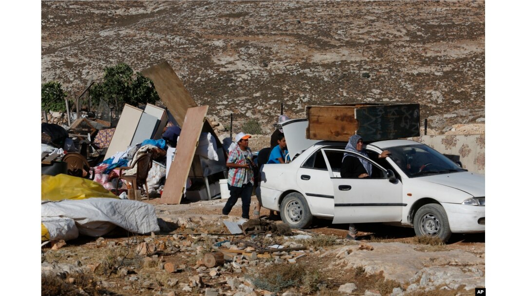 In this Tuesday, August 16, 2016 photo, Palestinians pack their belongings after their family house was demolished by Israeli troops in the West Bank village of Sair, near the town of Hebron.