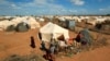 Refugees stand outside their tent at the Ifo Extension refugee camp in Dadaab, near the Kenya-Somalia border in Garissa County, Kenya on Oct. 19, 2011. 