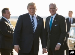 President Donald Trump stands on the tarmac with South Carolina Gov. Henry McMaster as he arrives on Air Force One at Greenville Spartanburg International Airport, in Greer, S.C., Monday, Oct. 16, 2017.