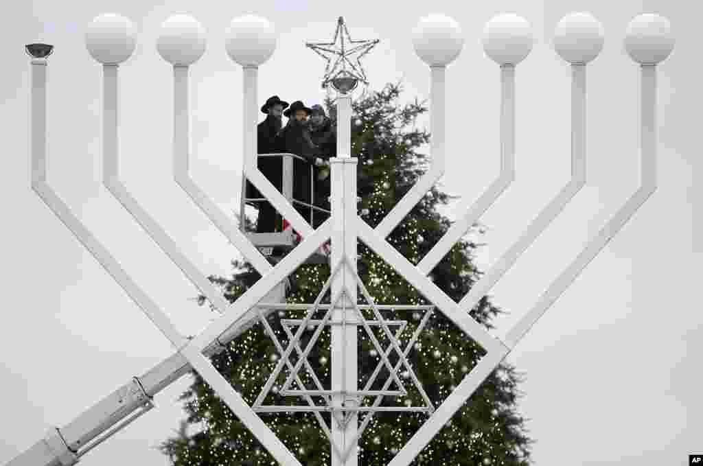 Cây đèn Menorah khổng lồ của dịp lễ Hanukkah, lễ hội ánh sáng của người Do Thái kéo dài tám ngày, trước một cây thông Giáng Sinh tại Cổng Brandenburg ở Berlin, Đức. 