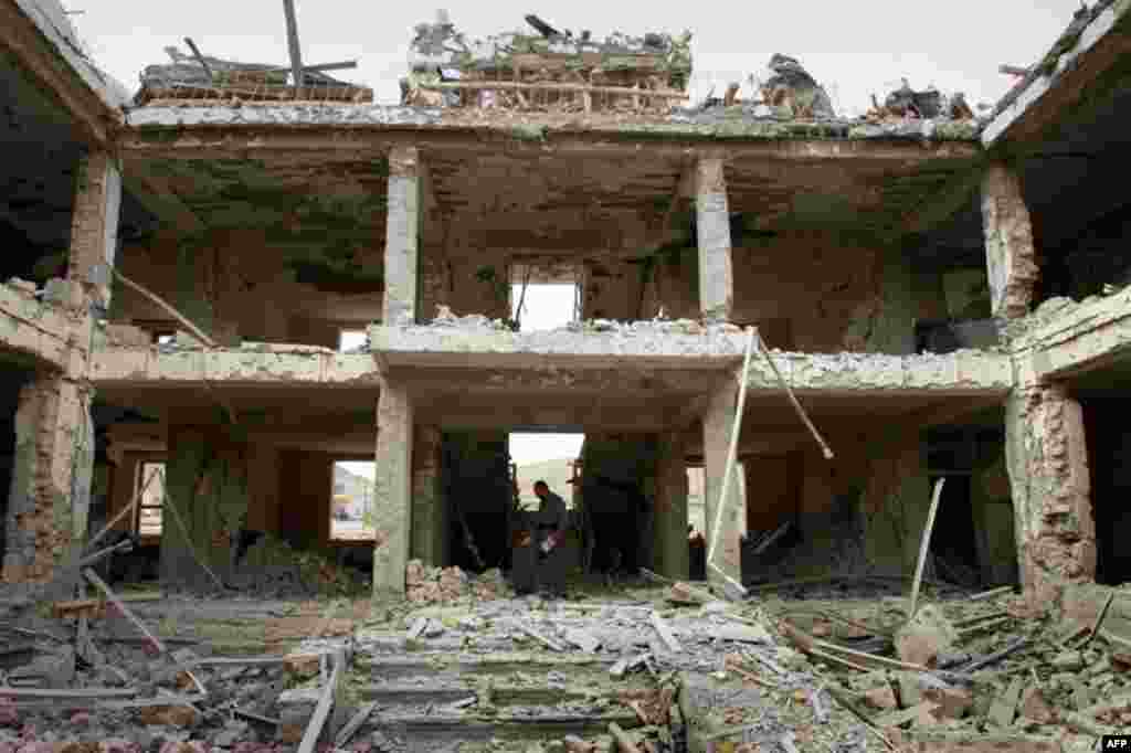 April 14: An Afghan police official investigates a damaged building at the scene of a suicide car bomb explosion on the outskirts of Kabul, Afghanistan. (AP)
