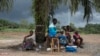 People suffering from the Ebola virus sit under a tree at Makeni Arab Holding Centre in Makeni, Sierra Leone, Oct. 4, 2014. 