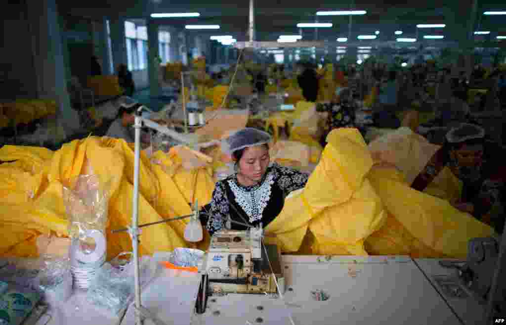 A woman sews a protective suit for use in handling people infected with the Ebola virus, in a sewing room of Lakeland Industries Inc., in Anqiu, China. 