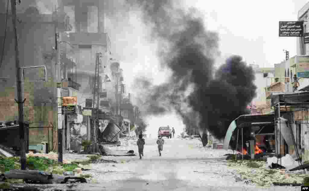 Para pemberontak Suriah berlari di jalanan kota Tayyibat al-Imam di provinsi Aleppo, Suriah.