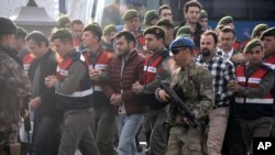 Paramilitary police escort the defendants as a trial opened in Mugla, southern Turkey, Monday, Feb. 20, 2017, for 47 people accused of attempting to kill President Recep Tayyip Erdogan on the night of the failed coup, while he was vacationing with his family.