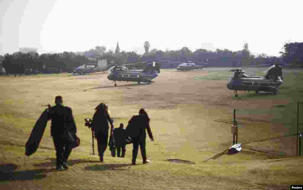 Members of the White House travelling staff walk to a group of helicopters about to transport U.S. President Barack Obama from a soccer field in Johannesburg, June 29, 2013. 