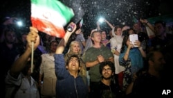 A group of jubilant Iranians cheer and spray artificial snow during street celebrations following the announcement of a landmark nuclear deal, in Tehran, July 14, 2015.
