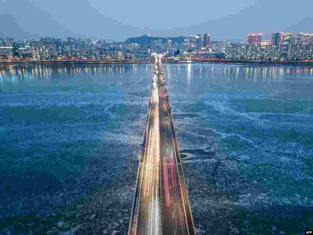 A general view of traffic passing over a bridge above the frozen Han river, before the Seoul city skyline, South Korea.