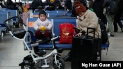 A child eats bread while waiting for a train at the South Train Station in Beijing, China on January 14, 2022. (AP Photo/Ng Han Guan)