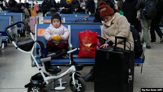 A child eats bread while waiting for a train at the South Train Station in Beijing, China on January 14, 2022. (AP Photo/Ng Han Guan)