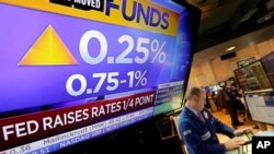 Specialist Edward Loggie works at his post as a television screen on the floor of the New York Stock Exchange shows the decision of the Federal Reserve, March 15, 2017.