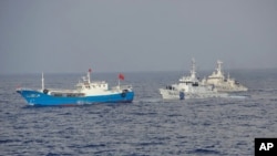 Japan Coast Guard patrol boats approach a Chinese fishing boat, left, off the northeastern coast of Miyako island, about 200 kilometers (124 miles) southwest of the disputed islands, called Senkaku in Japan and Diaoyu in China, February 2, 2013.