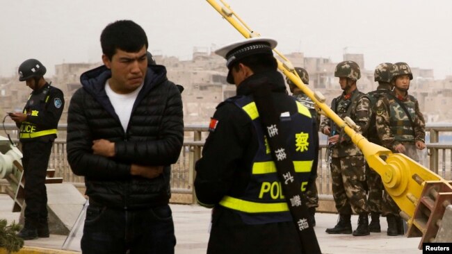 一名中国警察在新疆喀什检查一名男子的身份证件。（2017年3月24日）