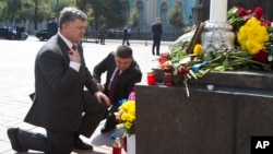 Ukraine's President Petro Poroshenko (L) and parliament speaker Volodymyr Groisman lay flowers by the photo of a police officer who was killed in violent clashes Monday, in front of Parliament in Kyiv, Ukraine, Sept. 1, 2015. 