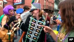 FILE - Image made from video shows a woman wearing a marching band costume taunts revelers with trinkets and beads in the Krewe of Cork parade in New Orleans, Feb. 22, 2019. 