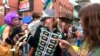 FILE - Image made from video shows a woman wearing a marching band costume taunts revelers with trinkets and beads in the Krewe of Cork parade in New Orleans, Feb. 22, 2019. 