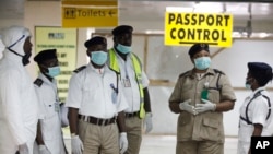 FILE - Nigeria health officials wait to screen passengers at the arrival hall of Murtala Muhammed International Airport in Lagos, Nigeria, Aug. 4, 2014. 