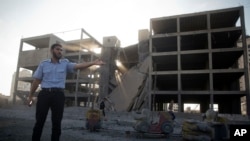 팔레스타인 경관이 가자지구에서 지난 14일 이스라엘 군의 공습으로 붕괴된 건물을 가리키고 있다.
