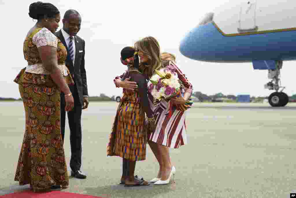 First lady Melania Trump embraces flower girl Lillian Naa Adai Sai, 8, as she receives flowers as she arrives at Kotoka International Airport in Accra, Ghana, Oct. 2, 2018. 