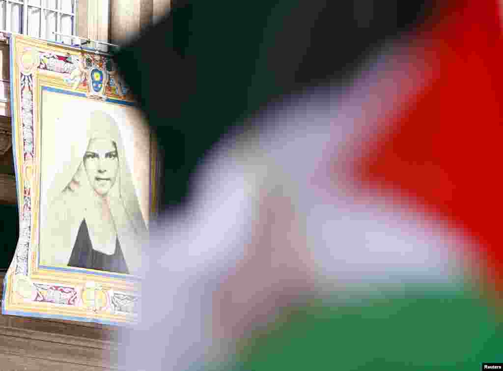 A Palestinian flag waves in front of a tapestry of Mariam Baouardy Haddad before Pope Francis leads a ceremony for the canonization of four nuns at Saint Peter&#39;s square in the Vatican City, May 17, 2015.