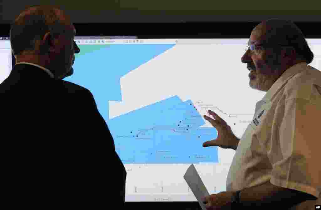 Mike Barton, ketua koordinasi penyelamatan (kanan), menunjukkan peta pencarian di Samudera Hindia pada Wakil PM Australia, Warren Truss di pusat koordinasi penyelamatan di Canberra (23/3). (AP/Graham Tidy)