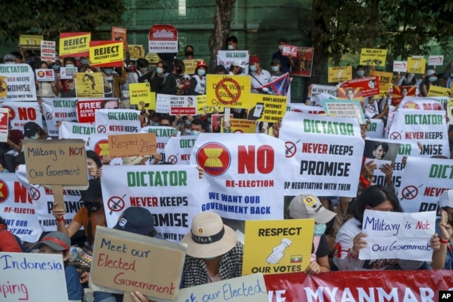 Pengunjuk rasa anti kudeta memegang plakat di dekat Kedutaan Besar Indonesia (KBRI) di Yangon, Myanmar, Rabu, 24 Februari 2021. (AP Photo)