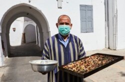 Foto ilustrasi - Seorang pria membawa kue di distrik Habous, Casablanca, Maroko, 23 Mei 2020. (AP)