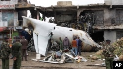 Soldiers look at the wreckage of the Fokker 50 cargo plane after it crashed, killing the four crew members aboard, shortly after takeoff at Kenyatta International Airport, Nairobi, Kenya, July 2, 2014. 