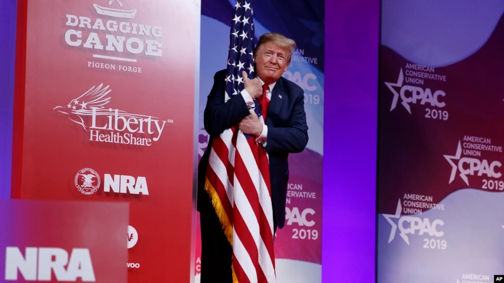 Tổng thống Trump ôm quốc kỳ Mỹ hôm 2/3.