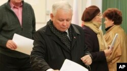 Pemimpin partai oposisi Hukum dan Keadilan (PiS) Polandia, Jaroslaw Kaczynski memasukkan kartu suara di sebuah TPS di Warsawa, Minggu (25/10).