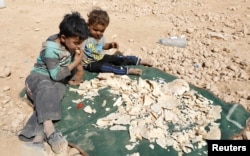 Children play near stale bread being dried under the sun at a refugee camp for people displaced because of fighting between the Syrian Democratic Forces and Islamic State militants, in Ain Issa, Syria, Oct. 14, 2017.