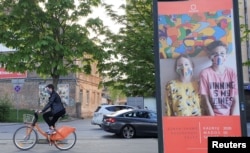 A bicyclist rides next to a billboard, a part of a "Mask Fashion Week" during the coronavirus disease (COVID-19) outbreak in Vilnius, Lithuania May 5, 2020. REUTERS/Andrius Sytas