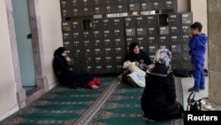 Syrian women rest at the entrance of a mosque in the neighborhood of Basmane, which is filled with transient migrants on their way to Europe, in the Aegean port city of Izmir, western Turkey, March 8, 2016. 