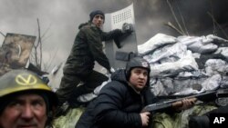 Kiev'de bir barikatın arkasında mevzilenen silahlı bir gösterici