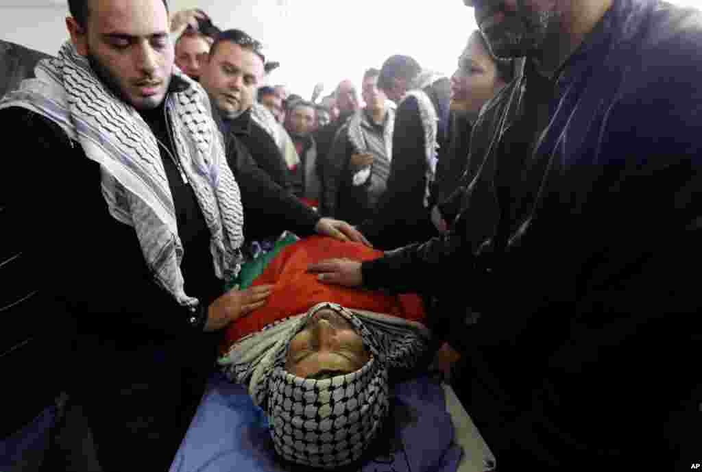 Mourners stand over the body of Palestinian Cabinet member Ziad Abu Ein during his funeral in the West Bank city of Ramallah, Dec. 11, 2014.