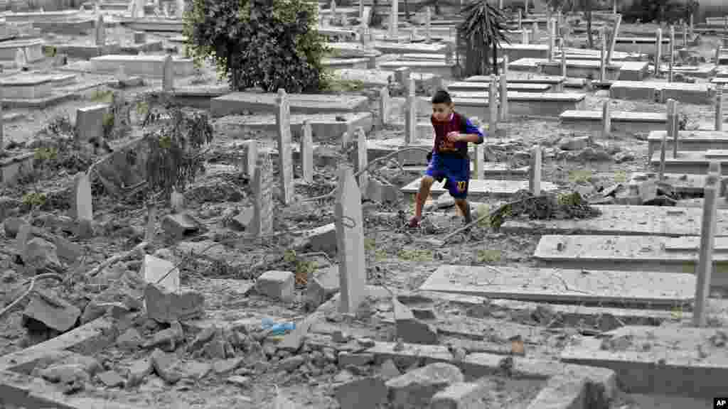 A Palestinian boy runs on rubble of damaged graves at a cemetery hit by an Israeli strike in Gaza City, Aug. 10, 2014.