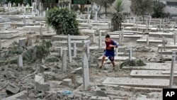 A Palestinian boy runs on rubble of damaged graves at a cemetery hit by an Israeli strike in Gaza City, Sunday, Aug. 10, 2014. 