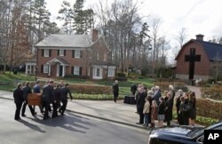Pall bearers carry the casket carrying the body of Billy Graham past family members to the Billy Graham Library in Charlotte, N.C., Feb. 24, 2018. Graham's body was brought to his hometown of Charlotte on Saturday as part of a procession expected to draw crowds of well-wishers.