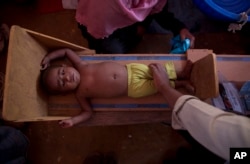 A volunteer measures the height of a Rohingya child at a health center at Balukhai refugee camp near Cox's Bazar, Bangladesh, Jan. 28, 2018.