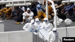 马耳他军人身穿防护服，把一名死亡船民的遗体抬离意大利海巡船。（2015年4月20日）