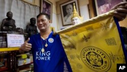 Korpsin Uiamsa-ard, a mentee of chief monk Phra Prommangkalachan at the Wat Traimitr Withayaram temple, holds up a Leicester City banner in Bangkok, Thailand, Tuesday, May 3, 2016.