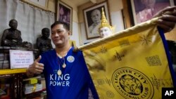 Biksu Korpsin Uiamsa-ard di kuil Wat Traimitr Withayaram di Bangkok, memegang bendera Leicester City (3/5).