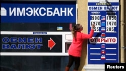An employee changes rates on a notice board at a currency exchange in Simferopol, March 17, 2014.