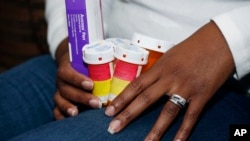 A patient holds the medications she takes to slow the progression of her multiple sclerosis, Feb. 24, 2015. (AP Photo/Rogelio V. Solis)