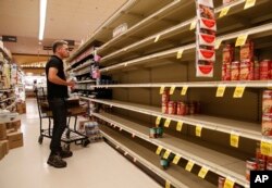 A worker looks at empty shelves for canned goods at a supermarket ahead of Hurricane Lane in Honolulu, Aug. 24, 2018.