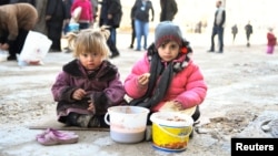 Girls eat a cooked meal provided by the U.N. through a partner NGO in the east Aleppo neighborhood of al-Bab, Syria, in this handout picture provided by UNHCR, Jan. 4, 2017.
