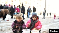 FILE - Girls eat a cooked meal provided by the U.N. through a partner NGO in the east Aleppo neighborhood of al-Bab, Syria, in this handout picture provided by UNHCR, Jan. 4, 2017.